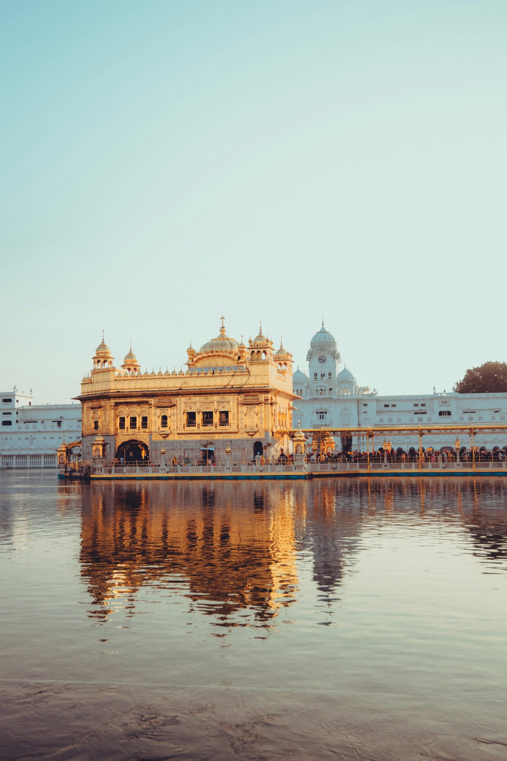 A serene view of the Golden Temple in Amritsar, its reflection shimmering in the tranquil water at sunrise.